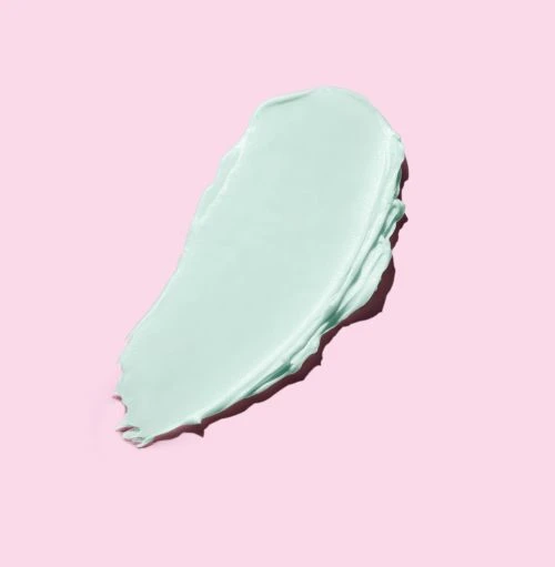 Macro studio shot of a turquoise-colored cosmetic cream swatch against a light pink background; ideal for beauty and skincare product promotion.