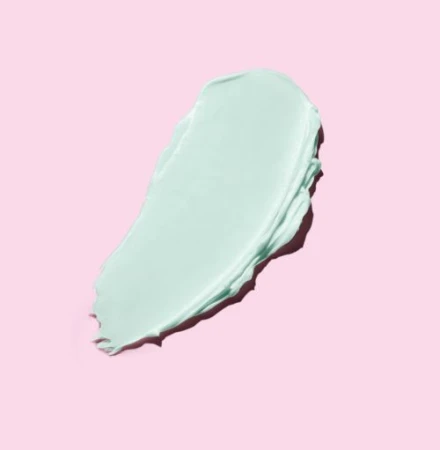 Macro studio shot of a turquoise-colored cosmetic cream swatch against a light pink background; ideal for beauty and skincare product promotion.