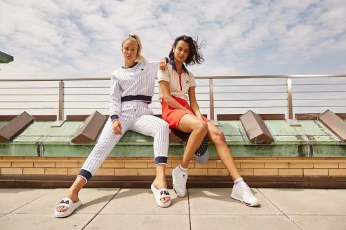 Two female models posing on a rooftop wearing sportswear styled by Calvy Click under clear skies