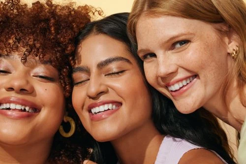 Close-up portrait of three smiling diverse women showing glowing skin and styled by wardrobe stylist Courtney Raniszewski