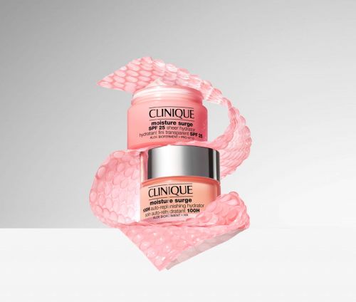 Clinique skincare products are stacked with pink, textured wrapping on a white surface against a soft grey gradient background.