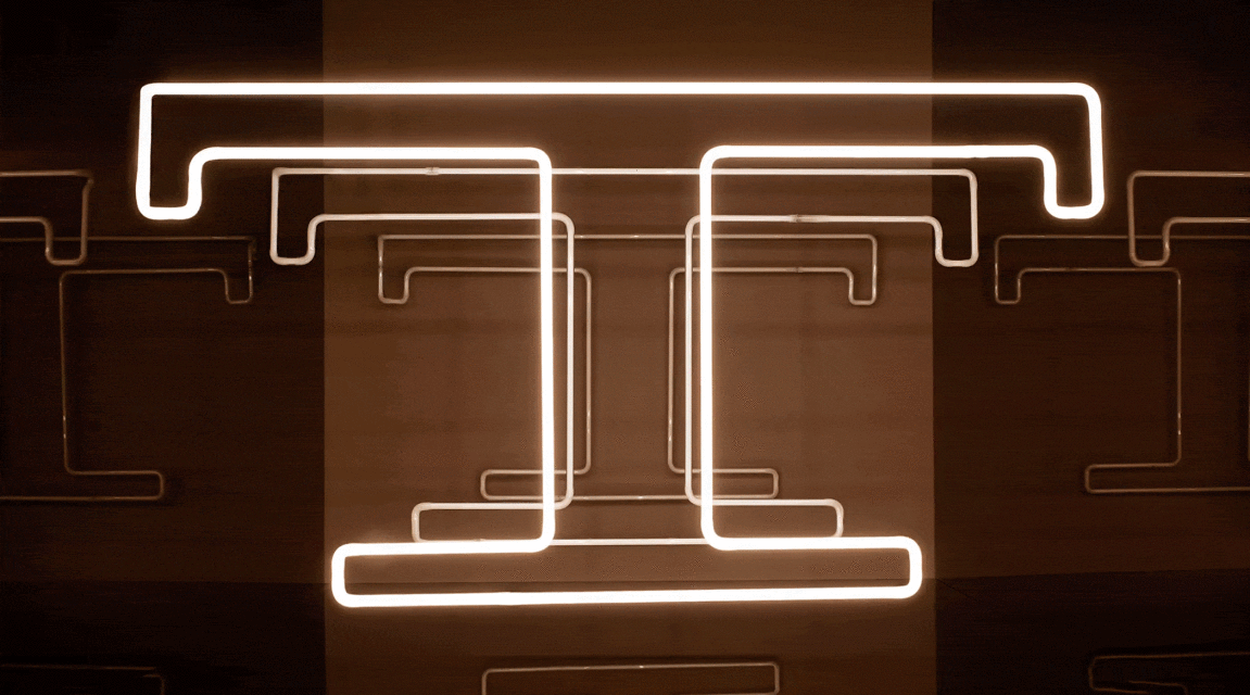 Abstract neon light art installation with geometric shapes on a dark brown background creates a modern, glowing design.