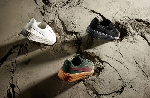 Three Puma platform sneakers are featured in black, white and dark green with dark red stripe, set against a cracked grey surface.