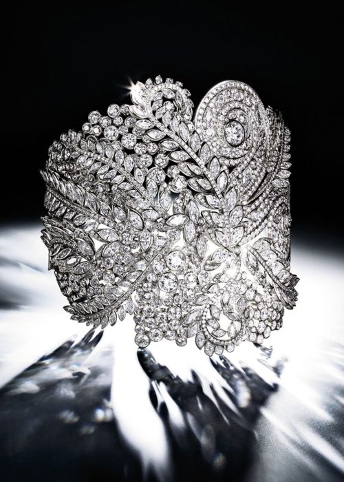 Close-up of an elaborate diamond cuff bracelet. Floral design set with sparkling diamonds, showcased in a dark and light setting.
