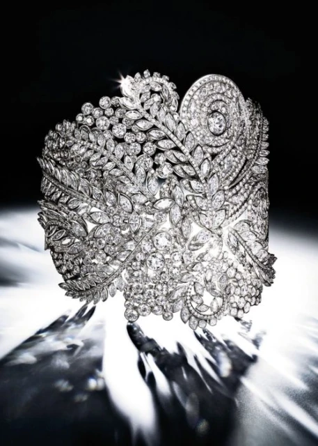 Close-up of an elaborate diamond cuff bracelet. Floral design set with sparkling diamonds, showcased in a dark and light setting.
