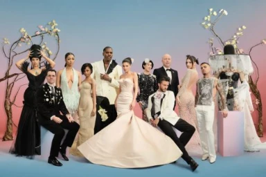 Group portrait of ten elegantly dressed individuals in formal wear and avant-garde gowns posed against a gradient background.