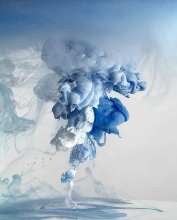 Artistic visual of flowing blue and white inks mixing in water, creating soft and dreamy abstract shapes against a neutral background.