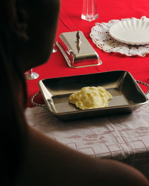 Silver tray holding head-shaped mashed potatoes on a white tablecloth with red accents, creating a unique food presentation.