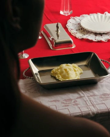 Silver tray holding head-shaped mashed potatoes on a white tablecloth with red accents, creating a unique food presentation.