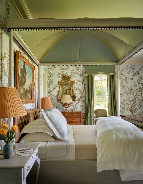 Elegant bedroom featuring a four-poster bed with floral wallpaper, complemented by warm lighting and a tranquil, inviting atmosphere.