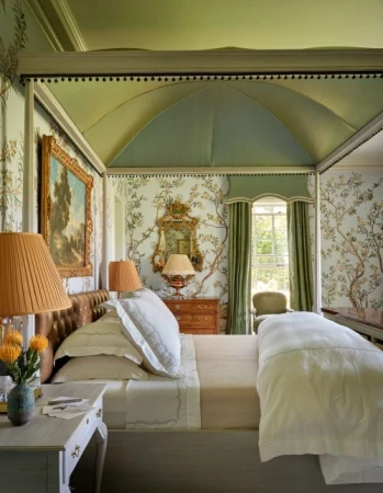 Elegant bedroom featuring a four-poster bed with floral wallpaper, complemented by warm lighting and a tranquil, inviting atmosphere.