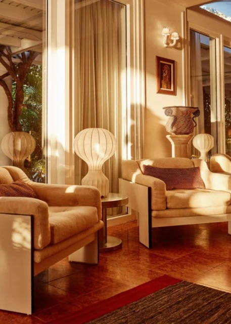 Cozy living room interior with two modern armchairs, stylish lamps, artwork, neutral color palette, and large windows with natural light.