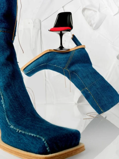 Surreal fashion still life with a denim boot, miniature chair, and white button-down shirts creating an artful, visually arresting composition.