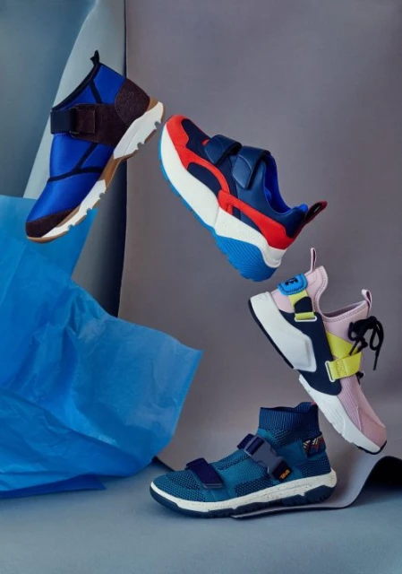 Five athletic sneakers arranged in a dynamic composition, showcasing a variety of designs and vibrant color combinations against a neutral backdrop.
