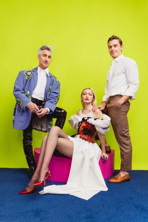 Three people pose in front of a bright green background, a woman sits on a pink block with two men standing on either side.
