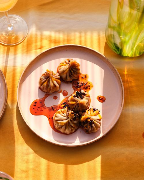Overhead shot of dumplings on a plate with sauce on a warm yellow background, creating a soft, inviting, and flavorful composition.