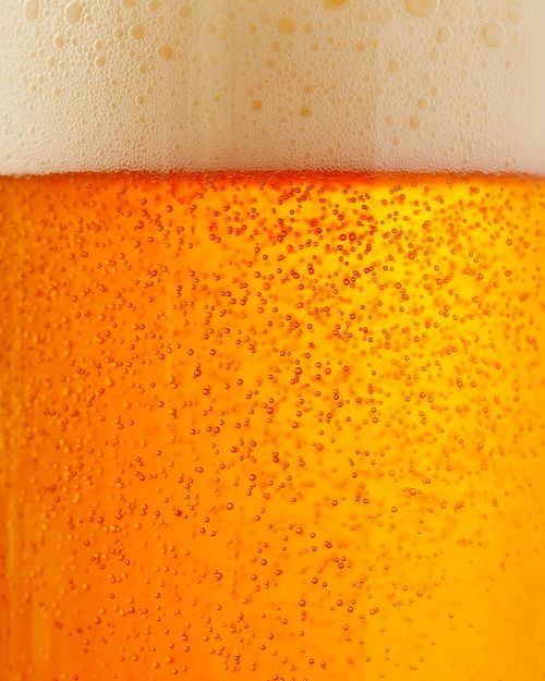 Close-up of a refreshing beer with golden liquid and frothy white foam, ideal for backgrounds and food & beverage visuals.