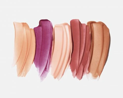 Swatches of various shades of lipstick and lip gloss are displayed on a white background, showcasing different colors and textures.
