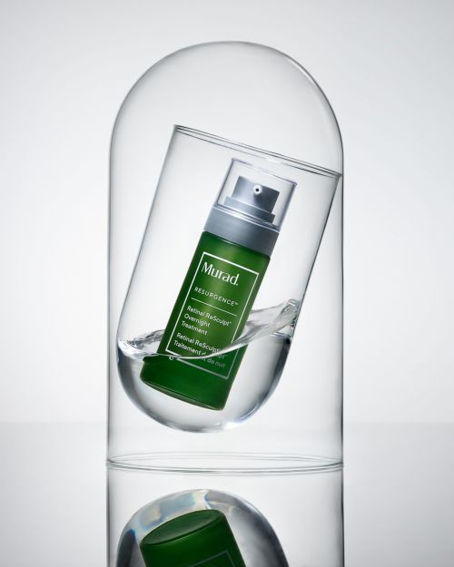 Murad Resurgence Retinol Reform Pro treatment bottle in a clear glass dome with water against a white background in a studio shot.
