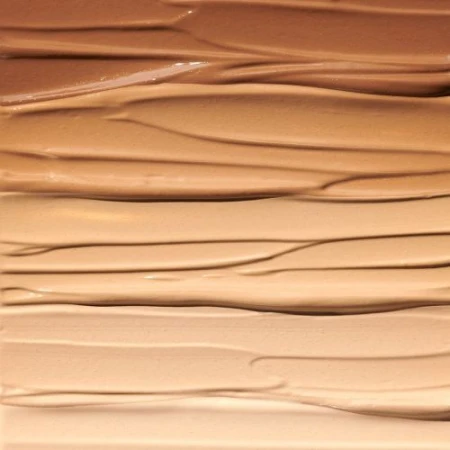 Close-up of cosmetic foundation swatches in various shades of beige, tan, and brown, showcasing smooth textures for beauty product marketing.