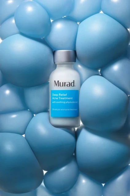 Murad Deep Relief Acne Treatment bottle surrounded by light blue balloons, product shot for beauty or healthcare brand.