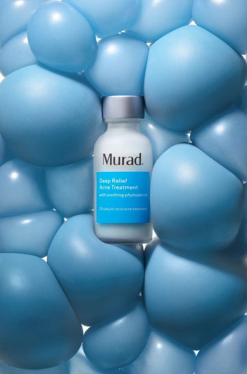 Murad Deep Relief Acne Treatment bottle stands out against a backdrop of light blue balloons, creating a playful and eye-catching display.