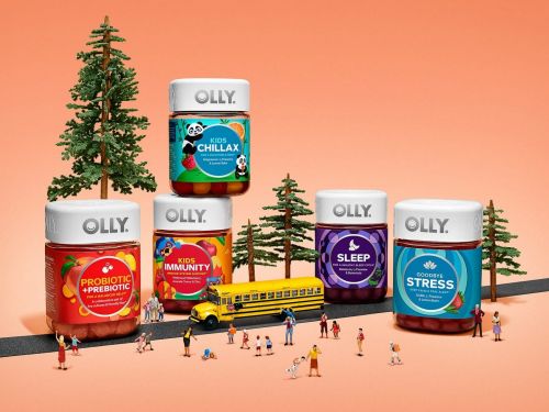 Five Olly supplement bottles are arranged near miniature figures, trees, and a school bus on a gradient orange background.