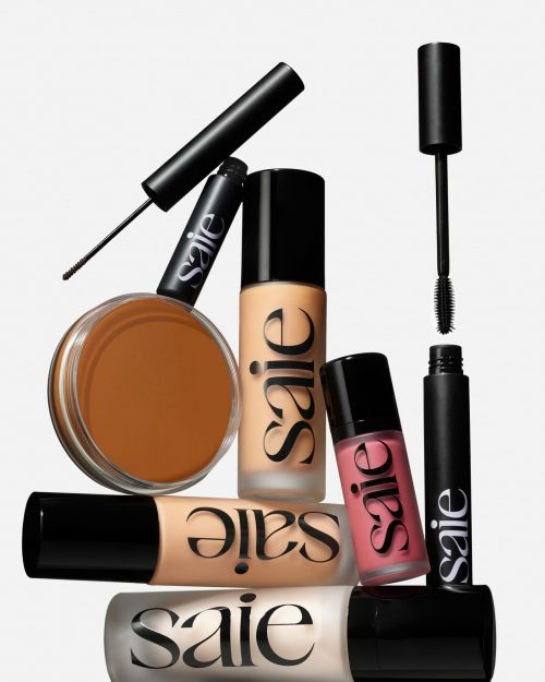 Cosmetic product arrangement: foundation, mascara, eyeliner, lip gloss against a white backdrop, beauty product flatlay.