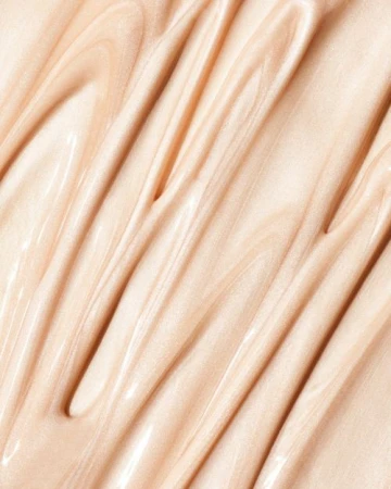 Close-up of swirling beige liquid cosmetic, creating a glossy and textured surface. Ideal for beauty or skincare product backgrounds.