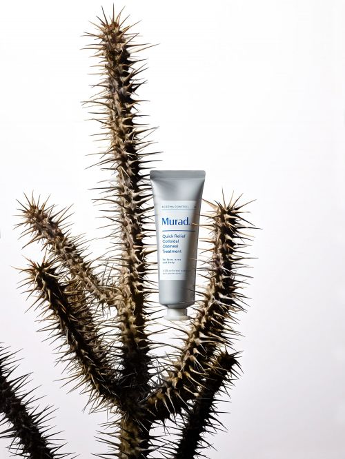 Murad skincare tube sits upright against a spiky plant with a bright white background, promoting beauty and skincare products.