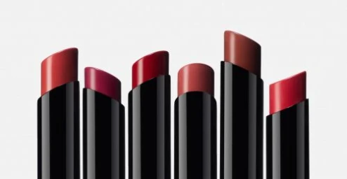 Six sleek black lipstick tubes with slanted red and berry shades arranged in a row against a clean white background.