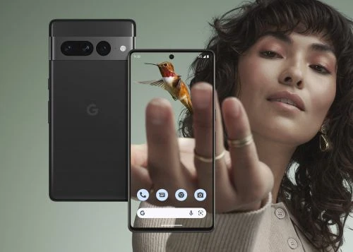 Woman showcasing a Google Pixel phone displaying a hummingbird image, another Pixel phone in the background, neutral studio setting.