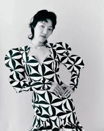 Model in black and white geometric print dress with statement puffed sleeves posing against a plain background