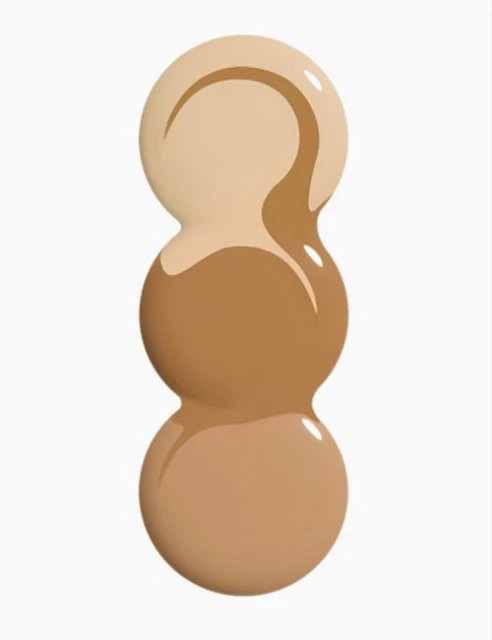 Three stacked drops of different shades of liquid foundation, ranging from light beige to medium tan, on a white background.