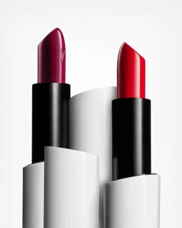 Two tubes of lipstick with contrasting red and plum shades positioned against a minimal white background