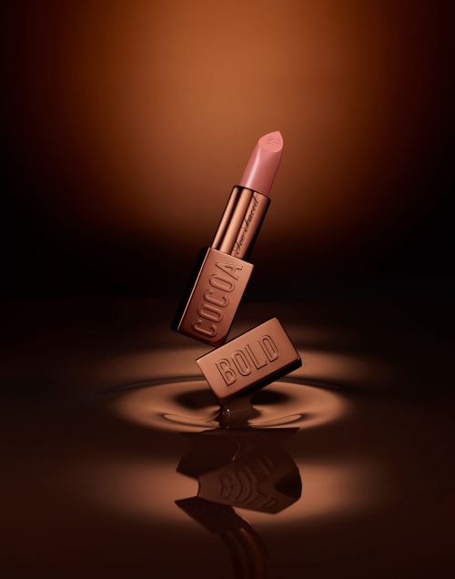 Elevated view of a Cocoa Bold lipstick tube, with the cap slightly separated and a chocolate ripple effect at the base.