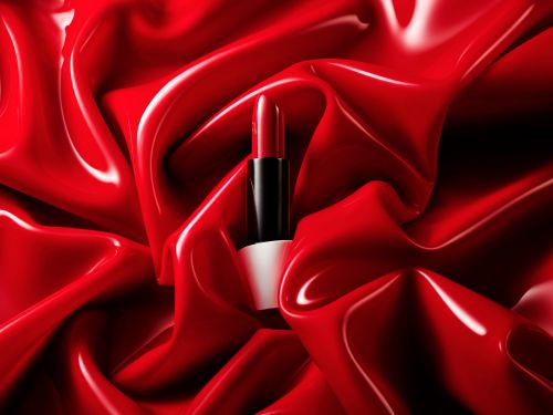 Close-up studio shot of red lipstick tube on a draped red background. Beauty and cosmetics photography for luxury brand marketing.