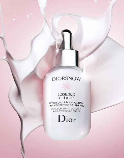 Dior serum bottle presented against a backdrop of milk splashes and a soft pink gradient, ideal for beauty and skincare advertising.