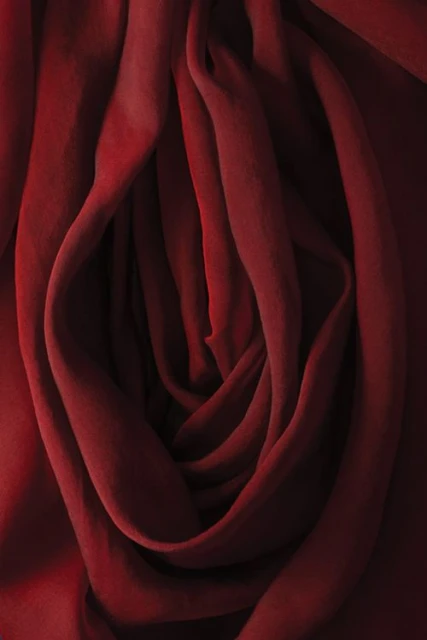 Burgundy fabric drapes and folds create a soft, flowing texture with deep shadows and rich color variations for a luxurious feel.