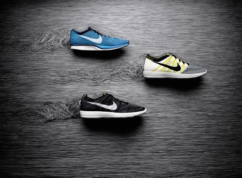 Three Nike running shoes are displayed in a studio setting with a textured dark background. The shoes are in black, blue, and gray.