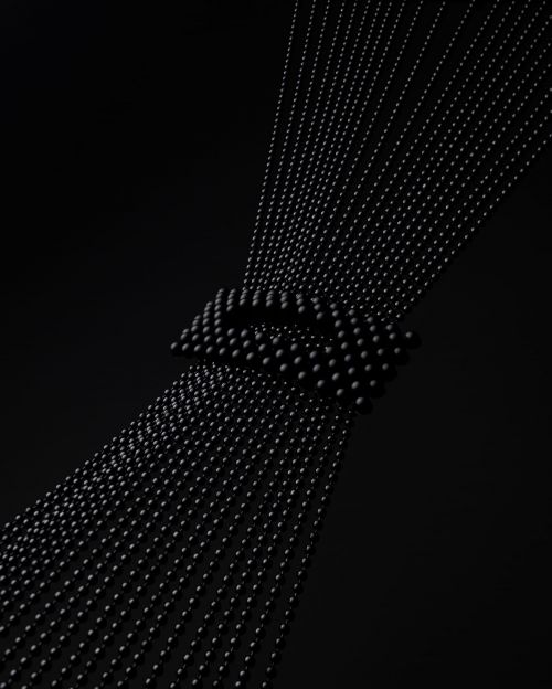 Abstract arrangement of evenly spaced strings of black beads converging in the center against a dark, gradient black background.