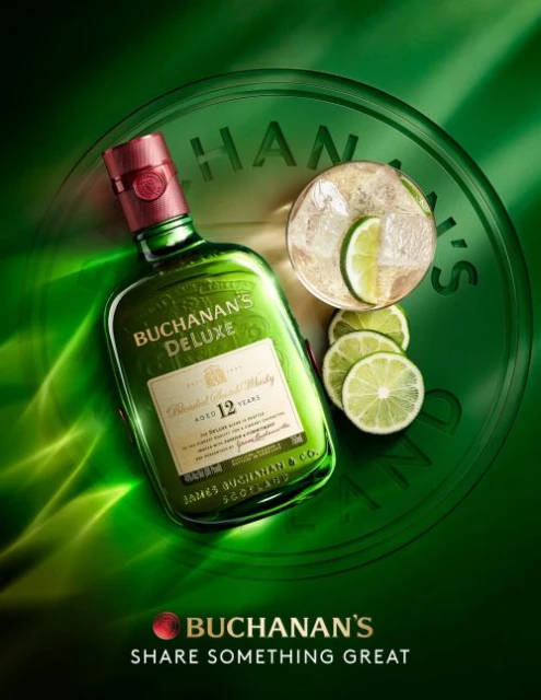 Buchanan's Deluxe whiskey bottle with a red cap, a glass of clear liquid with ice, and lime slices against a green background.