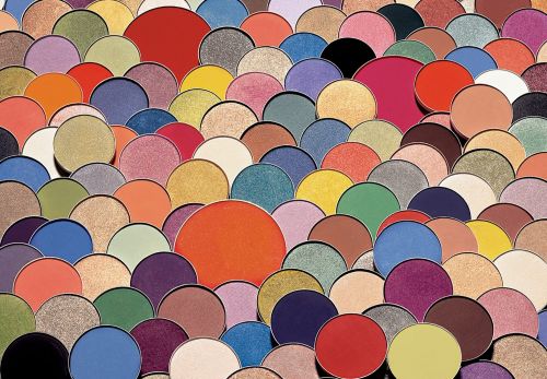 Overlapping circles of cosmetic powder in various colors, arranged to create a colorful, textured full frame pattern. 