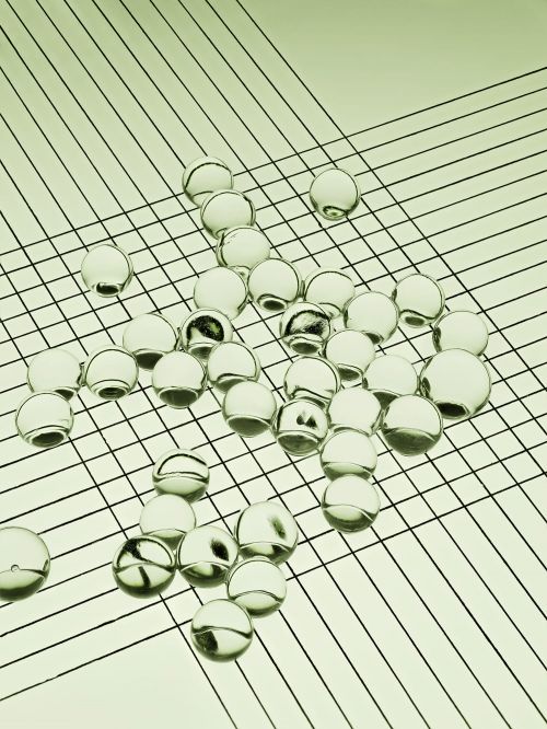 Translucent spheres scattered on a surface with linear pattern creating a geometric composition and minimalist aesthetic, close-up shot.