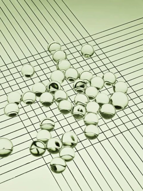 Translucent spheres scattered on a surface with linear pattern creating a geometric composition and minimalist aesthetic, close-up shot.