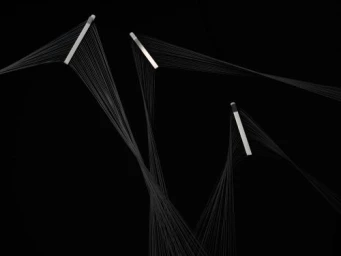 Minimalist prop sculpture featuring three geometric rods with radiating black threads against a solid black background.