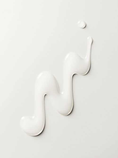 Artistic arrangement of white cosmetic cream with a spiral design on a light grey backdrop, capturing a modern, minimalist aesthetic.
