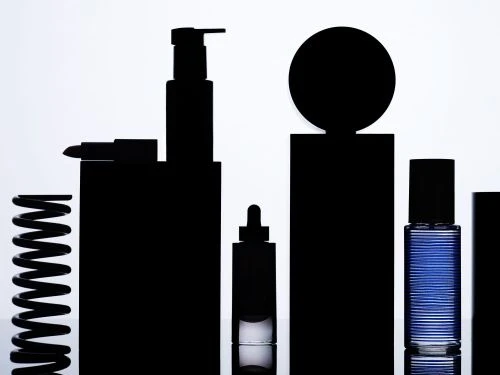 Silhouetted black cosmetic product bottles against a bright white background, creating a modern and minimalist beauty product display.