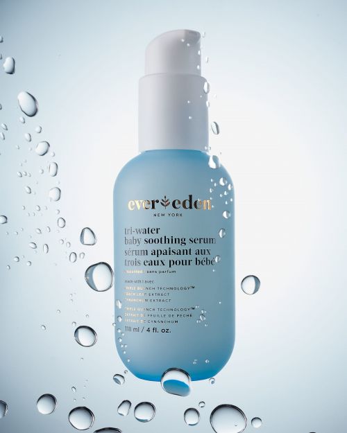Product shot of Ever Eden Tri-Water Baby Soothing Serum, a light blue and white bottle with water droplets against a light blue gradient background.