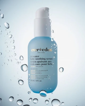 Product shot of Ever Eden Tri-Water Baby Soothing Serum, a light blue and white bottle with water droplets against a light blue gradient background.